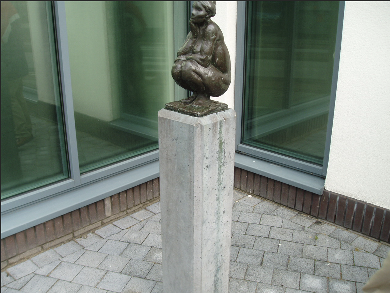 Bronzen vrouwenfiguur op stenen sokkel voor gebouw gevel