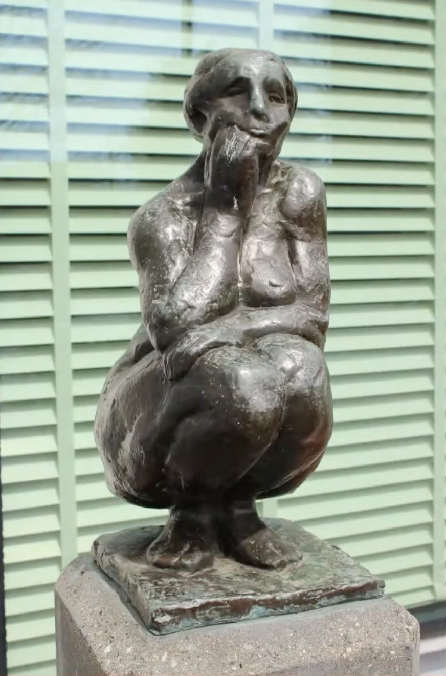 Bronzen vrouwenfiguur op stenen sokkel voor gebouw gevel