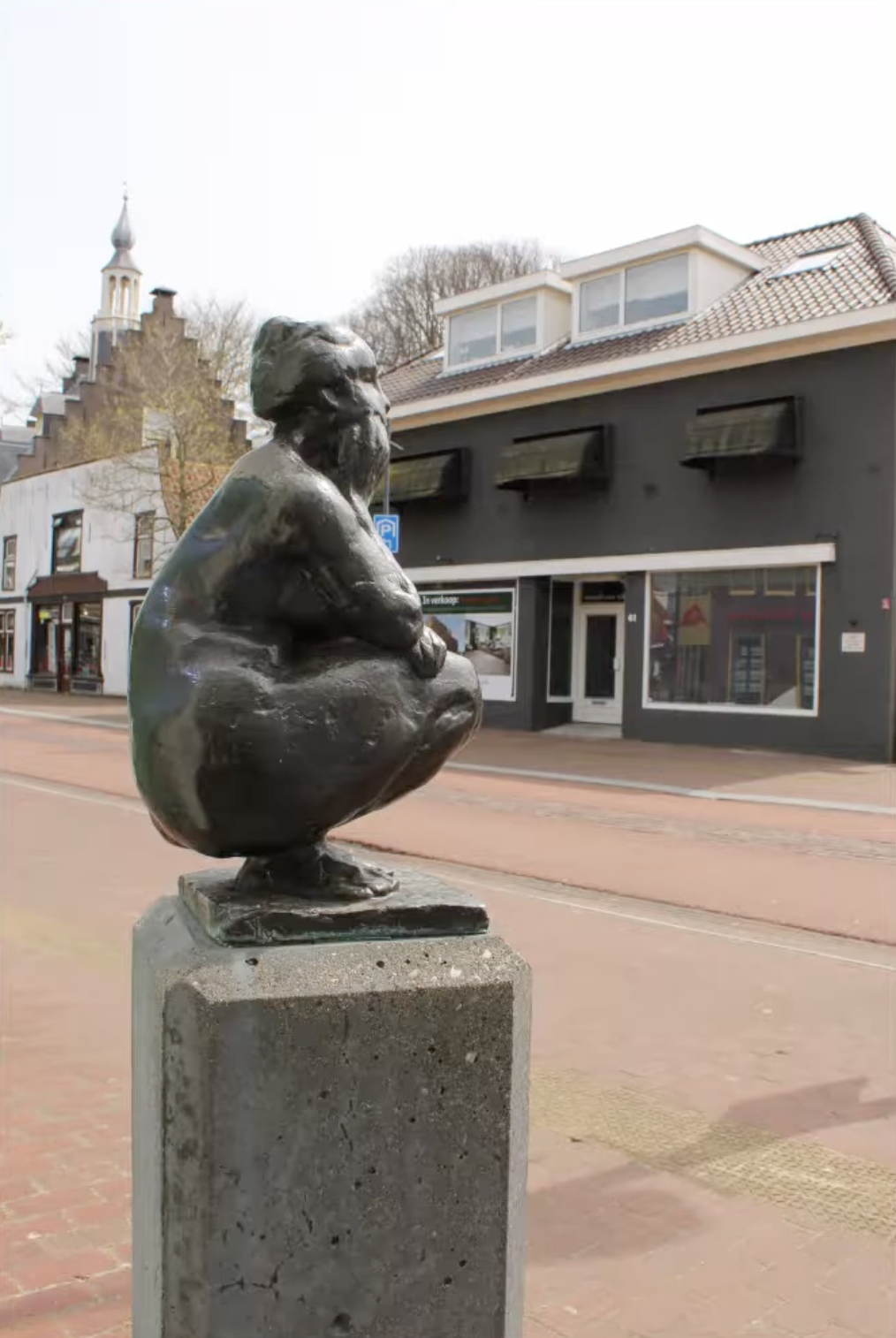 Bronzen vrouwenfiguur op stenen sokkel voor gebouw gevel