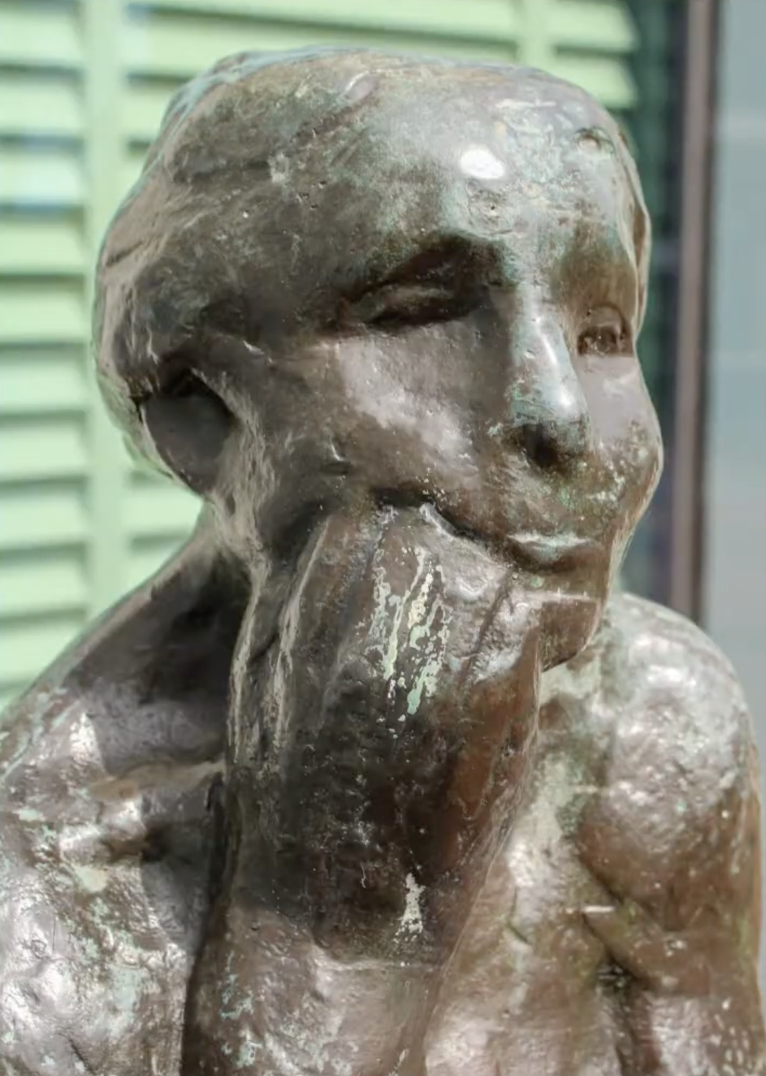 Bronzen vrouwenfiguur op stenen sokkel voor gebouw gevel